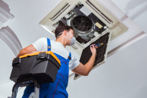 Worker repairing ceiling air conditioning unit